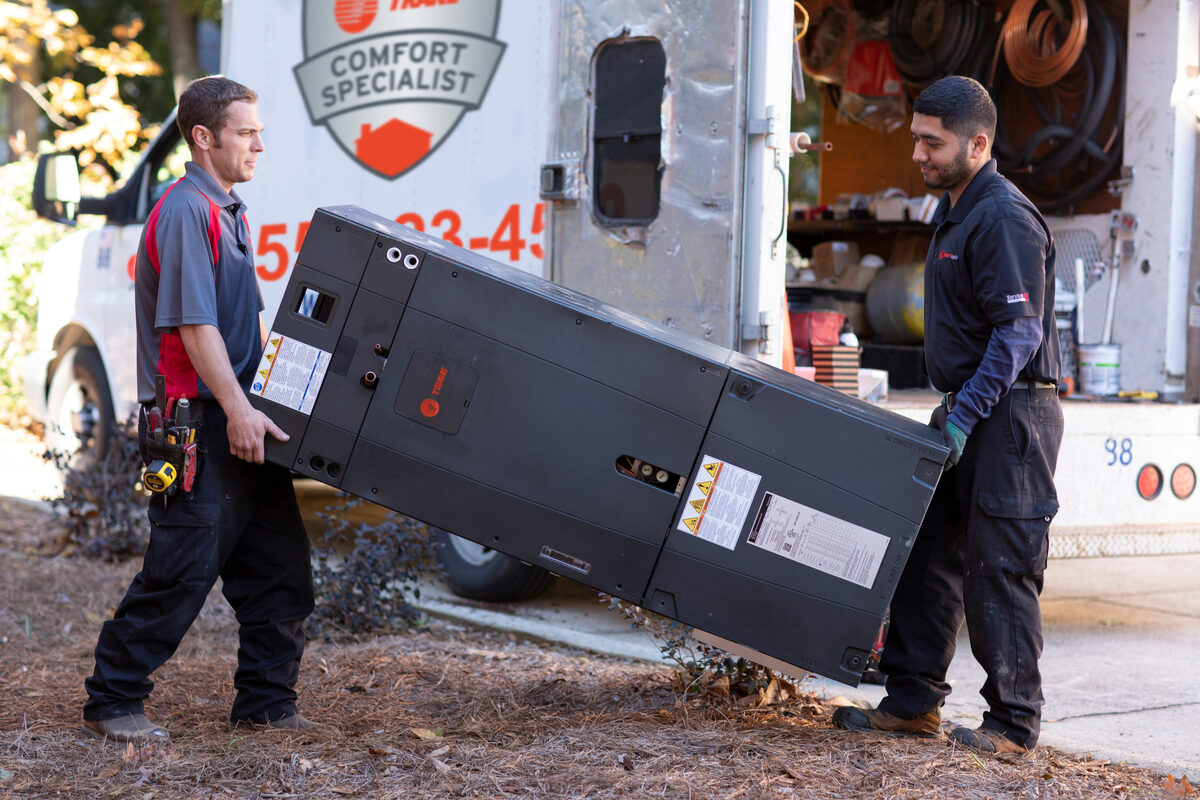 Technician installing or servicing a Trane heat pump outdoor unit
